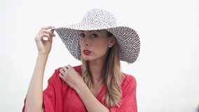Elegant model posing in red dress and hat on white background