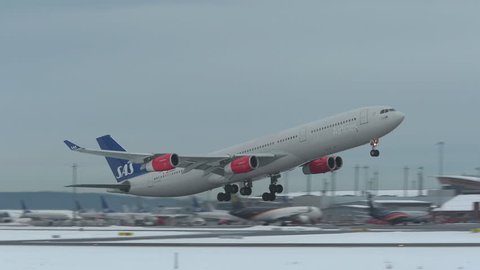 oslo airport norway - ca january 2019: huge airplane airbus a340 take off runway side view scandinavian airlines sas panning right slow motion