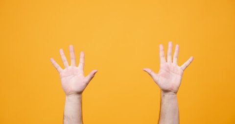 Male hands making different signs in studio over yellow background
