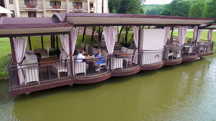 Aerial view. Two young people are sitting at a restaurant near the lake