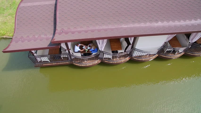Aerial view. Two young people are sitting at a restaurant near the lake