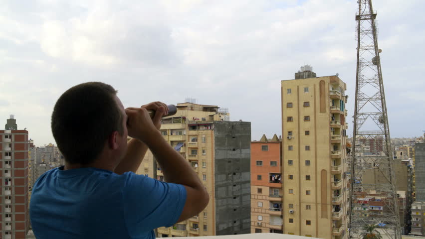 Man looks at the city through a telescope