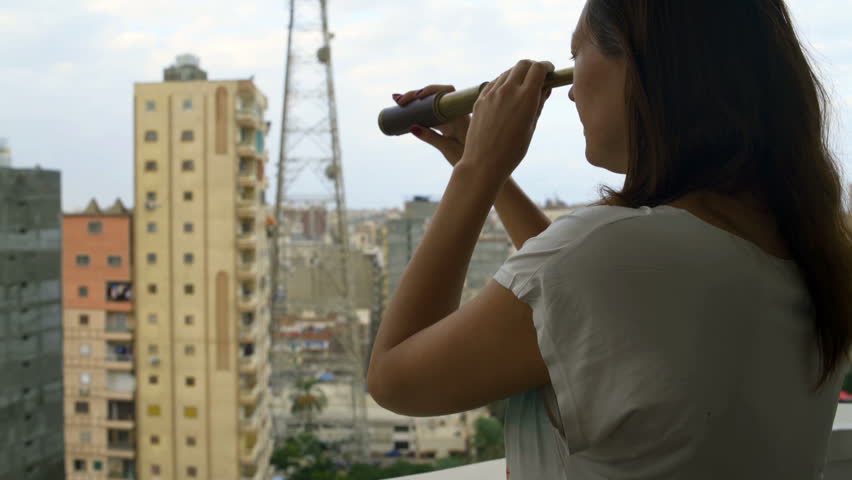 Woman looking at the city through a telescope