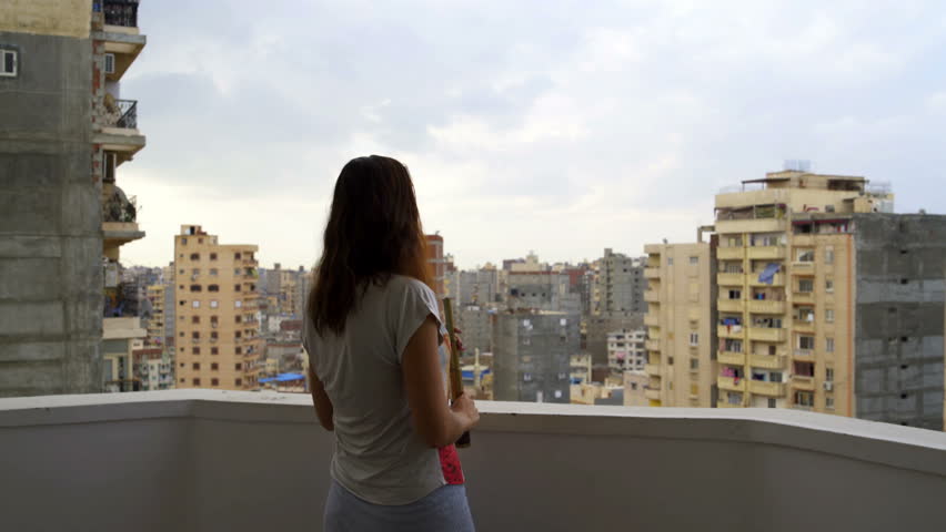 Woman looks at the city through a telescope