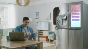 Beautiful Young Woman Opens the Fridge and Gives a Milk Bottle to Her Boyfriend. Then She Checks the Futuristic Digital To-Do List on the Smart Fridge Door. - Powered by Shutterstock - Get 15% off with code: PIKWIZARD15