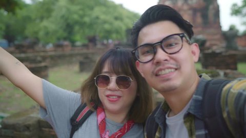 Traveler Asian couple using smartphone taking selfie while spending holiday trip at Ayutthaya, Thailand, Couple enjoy their journey at amazing landmark in traditional city. 