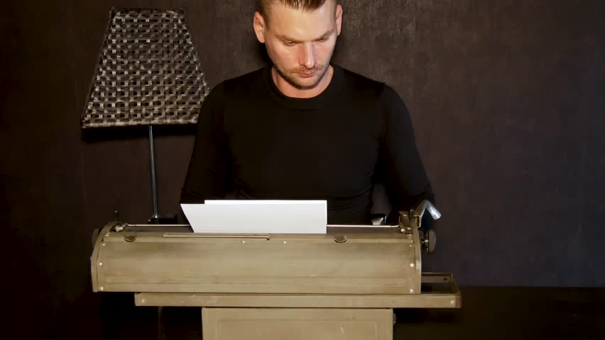 Man types on an old typewriter.