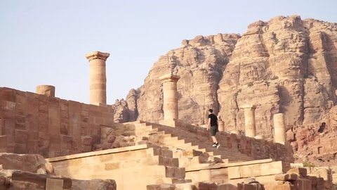 Tourist walking up ancient stairs in archaeological Petra, Jordan.