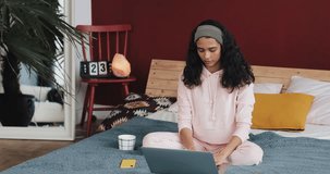 Beautiful young african american woman doing yoga exercise and watching tutorial lesson on laptop computer at home