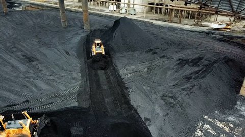 Crawler bulldozer works on coal mines. Extractive industry, anthracite. Aerial view.