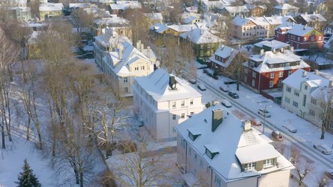 Snowy suburb street and colorful buildings in Europe. Aerial shot. Thick snow in the winter with sun shining onto colourful old and historical houses