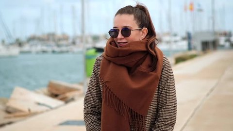Young pretty woman with big brown scarf walking near the sea in winter
