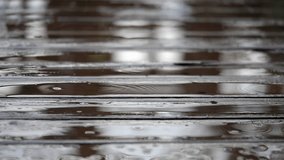 Close up slow motion video of raining drop splashing in the wooden footway on blur background (High Speed Video)