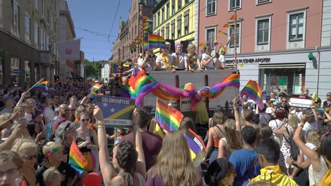 OSLO, NORWAY - JUNE 30, 2018: A lot of fancy-dress people with rainbow flags dance, sing and laugh in the street. The Pride Parade, the highlight of Oslo Pride Week, is a huge, vibrant parade filling