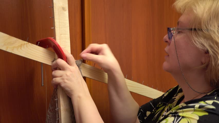 A woman removes a downy shawl from a special frame for stretching