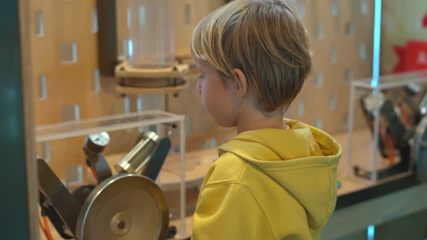 Little boy visits a science museum for children. He compresses air with a hand pump in order to make a plastic bottle fly up