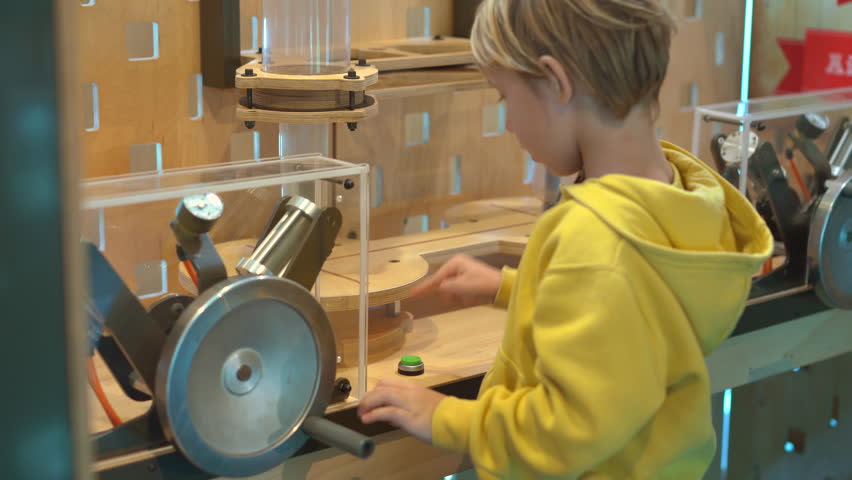 Little boy visits a science museum for children. He compresses air with a hand pump in order to make a plastic bottle fly up