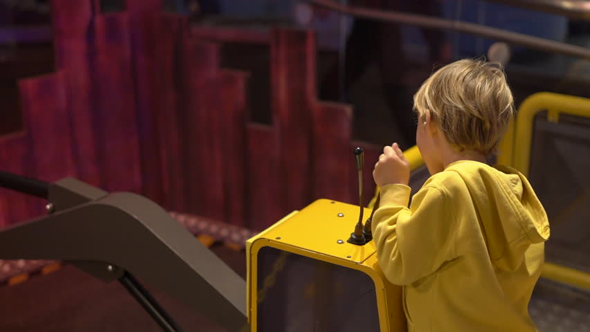 Slowmotion shot of a little boy visiting a science museum for children. Boy plays with a model of an excavator. Children trying different professions concept