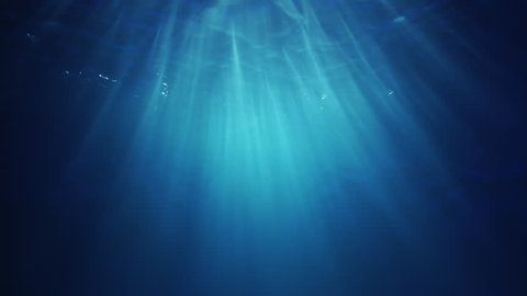 Underwater sunlight beams shining from above coming through the deep crystal clear blue water causing a beautiful water lighting reflections curtain