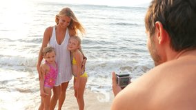 Family recording video on a beach at sunset
