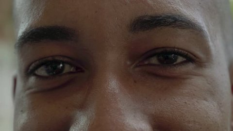Cropped shot of brown male eyes looking at camera. Close-up partial view of happy young African American man looking at camera. Emotion concept