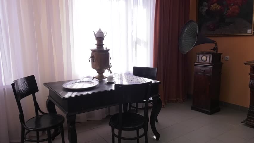 Vintage gramophone in the room on the bedside table. Room with vintage furniture, vintage gramophone. On the table is an old samovar.
