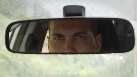 Young Caucasian Man Driving Car Looking in Rear View Mirror