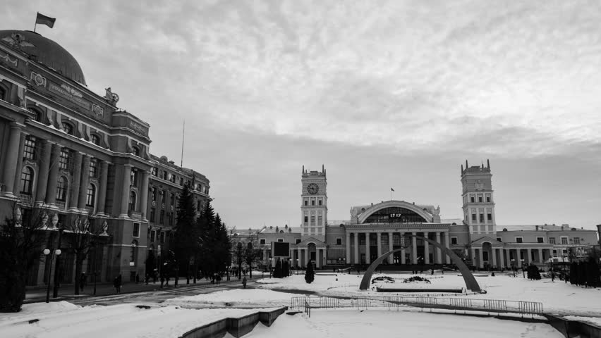 Kharkiv, Ukraine. Railway station in Kharkiv, Ukraine, at sundown on a snowy cloudy day. People walking by, time-lapse. Black and white