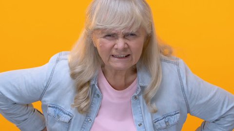 Disappointed granny looking angrily on yellow background, old generation, accuse