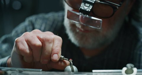 Slow motion of experienced goldsmith working on a handmade jewelry ring with precious diamond stones in a workshop. Shot in 8K. Concept of jewelry, luxury, goldsmith, diamonds, brilliance.