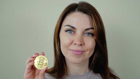 Young Woman holding physical bitcoin and ethereum cryptocurrency coins in her hands. young successful confident woman holds a gold bitcoin in her hand indoor. Woman holding a physical bitcoin
