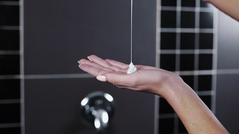 Close up shot of pouring shampoo to the woman's hand in the shower, hair cosmetics, hydration and nutrition, hair care and health
