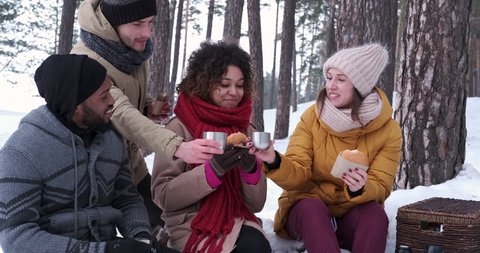 Young adults picnicking in snowy forest
