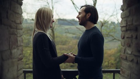 Portrait of an attractive Italian man and woman standing together showing each other affection with a beautiful landscape in the background with soft natural lighting. Medium shot on 4k RED camera.