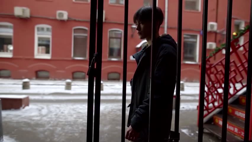 silhouette of young teenager boy are walking on street, going out from gate of yard of houses