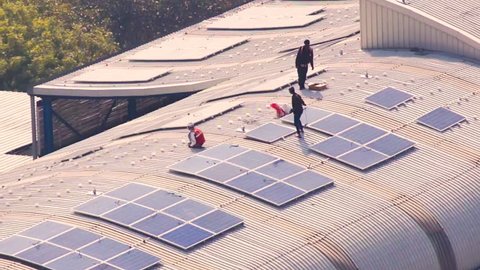 Aerial shot of workmen installing solar panels on the roof of metro station in Noida. These alternate and green power source power projects will help deliver clean energy to the stations. The iron