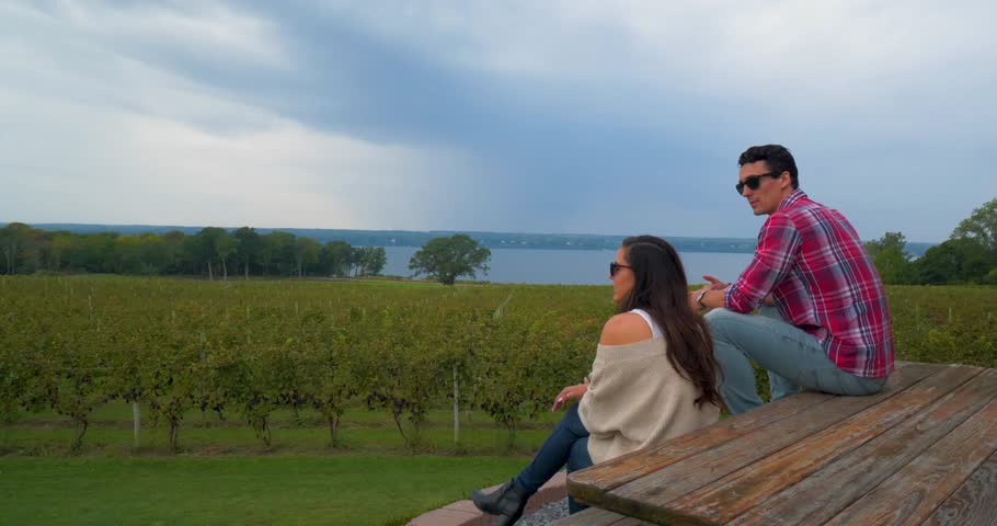 Couple Sits on Bench Overlooking Winery, Vineyard, at the Finger Lakes