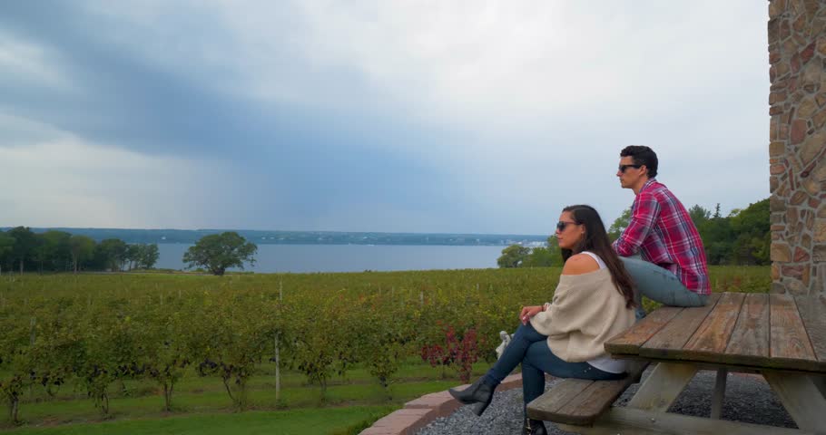 Couple Sits on Bench Overlooking Winery, Vineyard, at the Finger Lakes