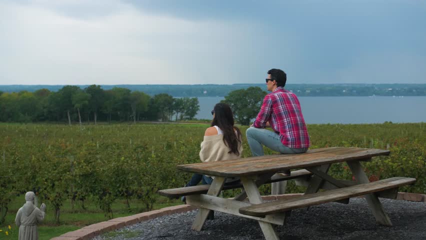 Couple Sits on Bench Overlooking Winery, Vineyard, at the Finger Lakes