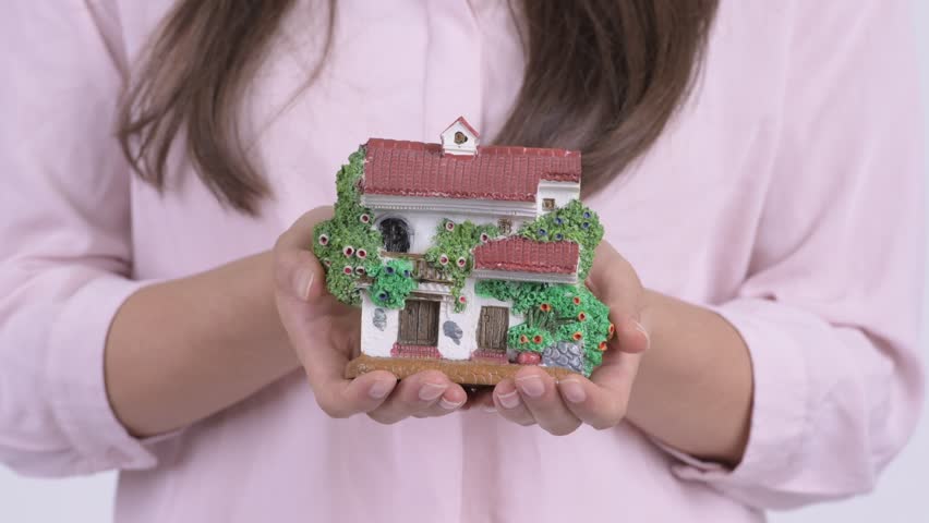 Young happy businesswoman holding house figurine