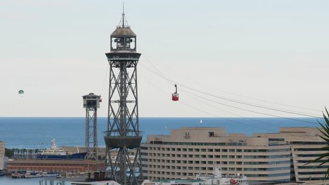 BARCELONA, SPAIN - AUGUST 18, 2018: Port Vell Aerial Tramway time lapse shot, small car move by steel ropes. Mediterranean sea on background. Grand Marina hotel building seen down, World Trade Center