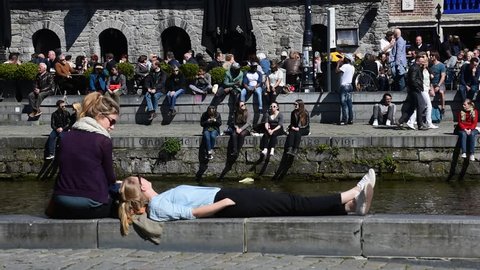 Ghent, Belgium - June 6, 2016. People enjoying the first spring sun by the waterside along the Graslei / Grass Lane at Ghent, Flanders, Belgium