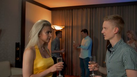 Woman and man communicate in flat apartment party, acquaintance and flirt. They happy, smile, laugh. Hints at the continuation of the evening in an intimate atmosphere, drinking champagne