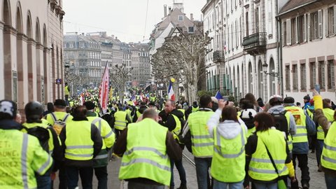 STRASBOURG, FRANCE - FEB 02, 2018: Rear view of thousands of Gilets Jaunes Yellow Vest manifestation on the 12 Saturday of anti-government demonstrations walking to Place Broglie