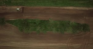 Farmer in tractor preparing land with seedbed cultivator. Agriculture. Tractor plowing field and preparing land for sowing near busy highway. Agronomy farming and husbandry concept. Aerial video.