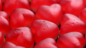Heart shaped jelly candy rotated love background. Red jelly sweets candies rotation backdrop. St. Valentines, love, marriage hearts background. Closeup. Slow motion 4K UHD video