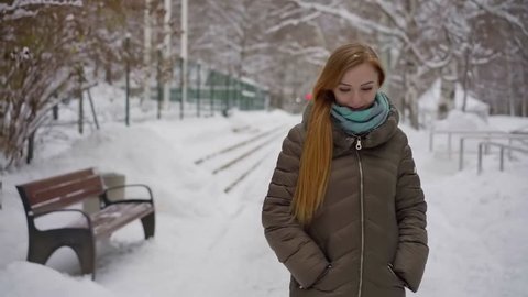 Charming blonde girl peacefully walking in a city park in in beautiful wintetime.