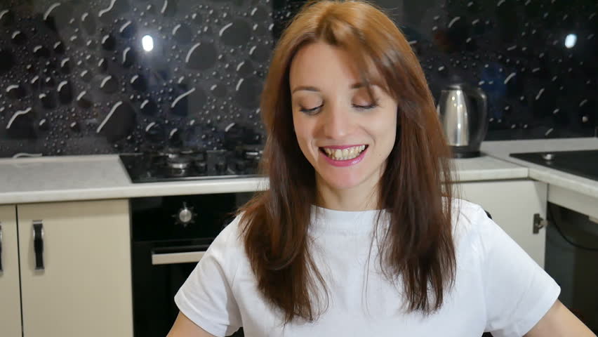 Attractive young woman playing with a donuts sitting at the kitchen at home