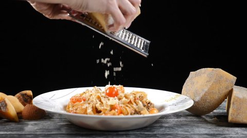 Chef grating hard cheese. Cooking seafood pasta. Slow motion of A cook grater cheese, typical Italian cheese, pasta on plate just freshly cooked Concept: Italian cuisine, cheese, restaurant and food