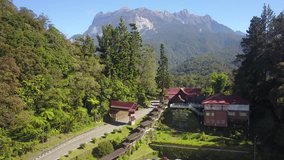 An aerial footage video of majestic mountain main entrance in Sabah Malaysia Borneo called Mount Kinabalu National Park. Slow moving drone view with green and blue mountain at background.